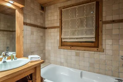 a bathroom with a tub and a sink and a window at Appartement des Epis - Welkeys in Megève