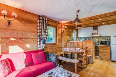 a living room with a red couch and a kitchen at Appartement des Epis - Welkeys in Megève