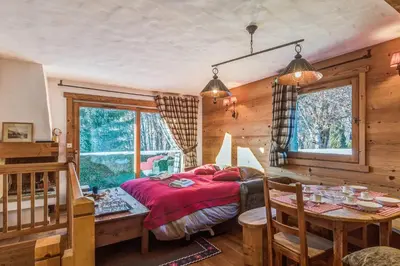 a bedroom with a bed and a table and a dining room at Appartement des Epis - Welkeys in Megève