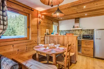 a kitchen with a wooden table and a dining room at Appartement des Epis - Welkeys in Megève