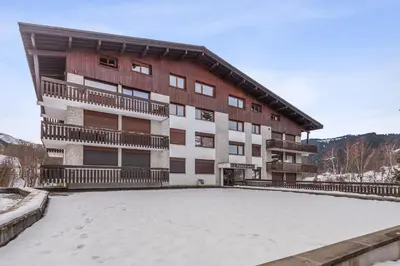 an apartment building with a large snow covered parking lot at Appartement Perchets - Welkeys in Megève