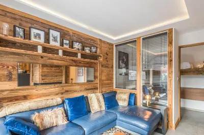 a living room with a blue couch and wooden walls at Appartement Perchets - Welkeys in Megève