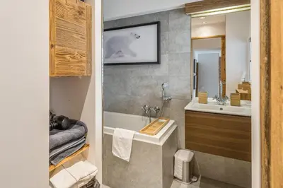 a bathroom with a tub and a sink and a mirror at Appartement Perchets - Welkeys in Megève