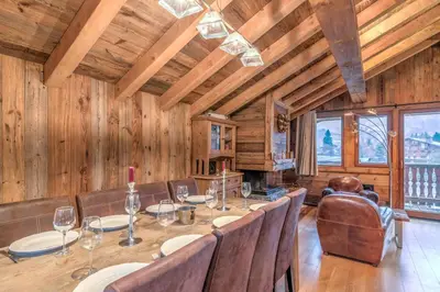 a dining room with a table and chairs and wooden walls at Chalet du Jaillet - Welkeys in Megève
