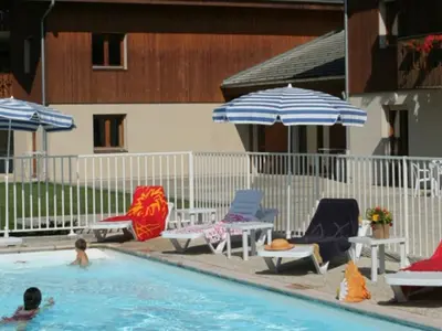 a pool with chairs and umbrellas and people in the water at Appartement 2 pièces avec balcon à Samoëns, parking inclus - FR-1-629-121 in Samoëns