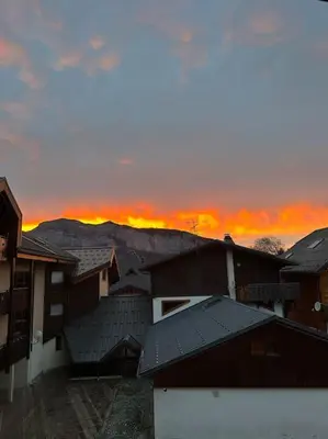 a group of houses with the sunset in the background at Studio Hyper centre in Les Carroz d'Araches