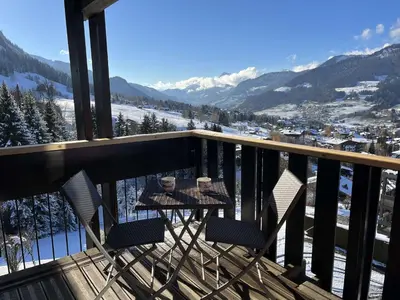 a table and two chairs on a balcony with mountains at Appartement 3 pièces + cabine à Megève, 6 couchages, proche pistes et téléphérique - FR-1-597-170 in Megève
