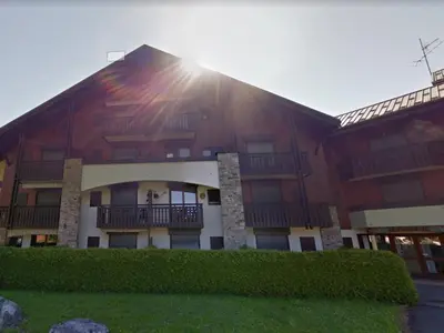 a large building with the sun shining on it at Charmant T2 proche du centre avec parking - FR-1-624-127 in Samoëns