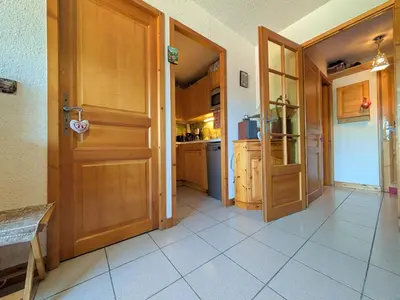 a kitchen with a wooden door and a white tile floor at Charmant T2 proche du centre avec parking - FR-1-624-127 in Samoëns