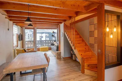 a dining room with a wooden table and a staircase at Refuge de l'Aiguille - 2 bedroom duplex in the heart of Chamonix in Chamonix-Mont-Blanc