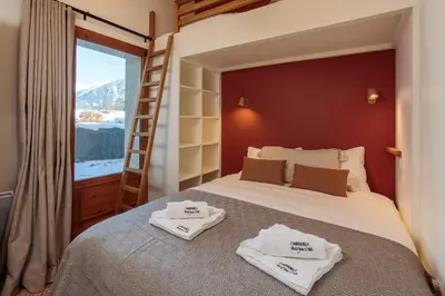 a bedroom with a bed with a ladder and towels at Miremont Apartment - Chamonix All Year in Chamonix-Mont-Blanc