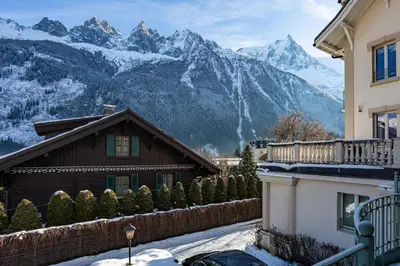 a house with snow covered mountains in the background at Miremont Apartment - Chamonix All Year in Chamonix-Mont-Blanc