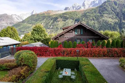a house with a table in a garden with mountains at Miremont Apartment - Chamonix All Year in Chamonix-Mont-Blanc