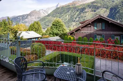 a balcony with a table and chairs and a house at Miremont Apartment - Chamonix All Year in Chamonix-Mont-Blanc