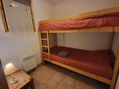 a bedroom with two bunk beds and a desk at Ecrins A4, 1 bedroom apartment with bunk room, central Samoëns in Samoëns