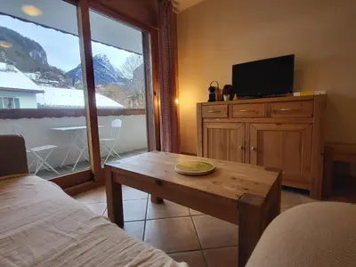 a room with a bed and a table and a tv at Ecrins A4, 1 bedroom apartment with bunk room, central Samoëns in Samoëns