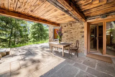 a patio with a wooden ceiling and a table and chairs at Chalet Ananda avec Sauna, Baignoire Balnéo et Terrasse in Chamonix-Mont-Blanc
