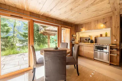 a kitchen with a table and a large window at Chalet Ananda avec Sauna, Baignoire Balnéo et Terrasse in Chamonix-Mont-Blanc