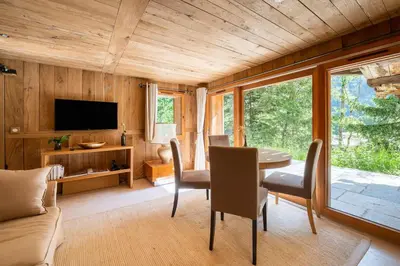 a living room with a table and chairs and a television at Chalet Ananda avec Sauna, Baignoire Balnéo et Terrasse in Chamonix-Mont-Blanc