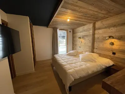 a bedroom with a bed with a wooden wall at Appartement 5 pièces au pied des pistes, 8 pers, avec parking et WiFi - FR-1-572-277 in Arâches-la-Frasse