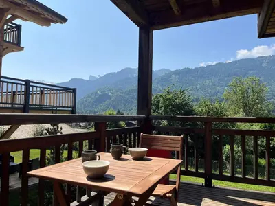 a wooden table on a deck with a view of mountains at Appartement lumineux T3 pour 4-6 pers avec WIFI et parking à Samoëns - FR-1-624-128 in Samoëns