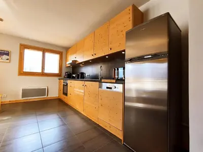 a kitchen with wooden cabinets and a stainless steel refrigerator at Appartement lumineux T3 pour 4-6 pers avec WIFI et parking à Samoëns - FR-1-624-128 in Samoëns