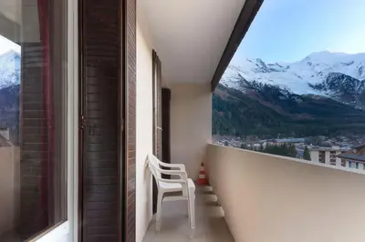 a white chair sitting on a balcony with a view of mountains at Les Pècles Mt Blanc - Chamonix Center in Chamonix-Mont-Blanc