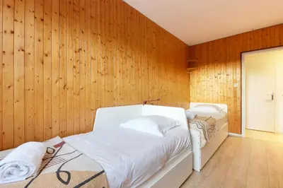 two beds in a room with wooden walls at Les Pècles Mt Blanc - Chamonix Center in Chamonix-Mont-Blanc