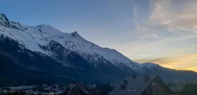 a snow covered mountain with a town in front of a city at Les Pècles Mt Blanc - Chamonix Center in Chamonix-Mont-Blanc