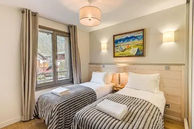 two beds in a room with a window at White Pearl A13 - Alpes Travel - Central Chamonix (Sleeps 6) in Chamonix-Mont-Blanc
