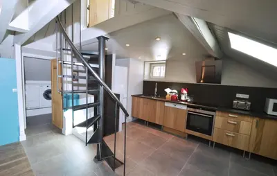 a kitchen with a staircase leading up to a loft at Appartement Bellevue - centre ville in Chamonix-Mont-Blanc