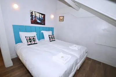a small bedroom with a white bed with pillows at Appartement Bellevue - centre ville in Chamonix-Mont-Blanc
