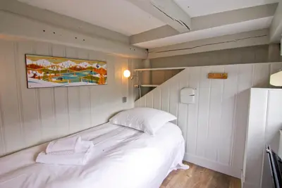 a bedroom with a white bed and a painting on the wall at Appartement Bellevue - centre ville in Chamonix-Mont-Blanc