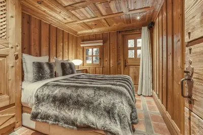 a bedroom with a bed in a room with wooden walls at Chalet Edelweiss in Megève