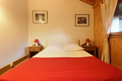 a bedroom with a bed with a red blanket at Chalet Ancelles - Les Praz - Golf - Vue Mont-Blanc - Randonnées in Chamonix-Mont-Blanc