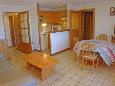 a living room with a table and a kitchen at Appartement cosy à Samoëns avec terrasse et parking - FR-1-629-72 in Samoëns