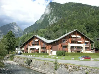 a large wooden building in front of a mountain at Appartement cosy à Samoëns avec terrasse et parking - FR-1-629-72 in Samoëns