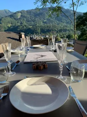 a table with a white plate and glasses on it at Pom Pom, 3 bedroom apt with stunning mountain views-Samoëns in Samoëns