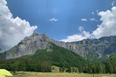 a mountain in the distance with people in a field at Pom Pom, 3 bedroom apt with stunning mountain views-Samoëns in Samoëns