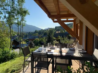 a table and chairs on a patio with a view at Pom Pom, 3 bedroom apt with stunning mountain views-Samoëns in Samoëns