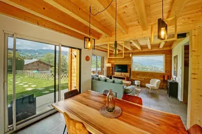 a dining room with a table and a living room at Magnifique Chalet neuf 8 pers, 800 m télécabine Princesse Megeve in Combloux