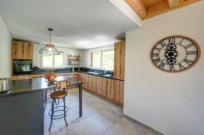 a kitchen with a table and a clock on the wall at Magnifique Chalet neuf 8 pers, 800 m télécabine Princesse Megeve in Combloux