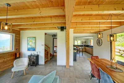 a dining room and living room with wood ceilings at Magnifique Chalet neuf 8 pers, 800 m télécabine Princesse Megeve in Combloux