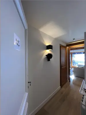 a hallway with a white wall with a lamp on it at N5 Megève - Résidence de L'ours - appart 4 pers in Megève