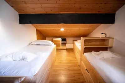 two beds in a room with wooden floors at Kinabalu - Vue Mt Blanc Range Les houches center in Les Houches