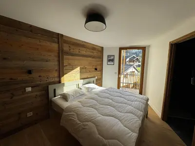 a bedroom with a large bed with a wooden wall at Appartement de standing, au pied des pistes avec parking et WIFI, Les Carroz d'Arâches - FR-1-572-280 in Arâches-la-Frasse