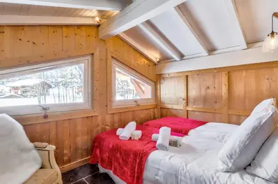 two beds in a room with wood paneling at La Suite Darray - Welkeys in Megève