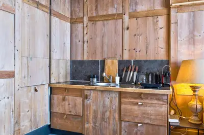 a kitchen with wooden walls and a counter with a sink at La Suite Darray - Welkeys in Megève