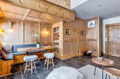 a room with wooden walls and a table and stools at La Suite Darray - Welkeys in Megève
