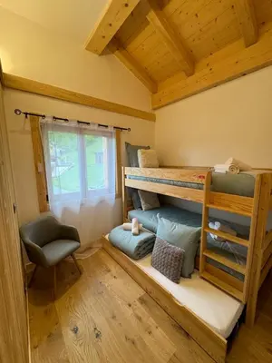 a room with two bunk beds and a chair at Chalet Clos du Nant Megève in Demi-Quartier